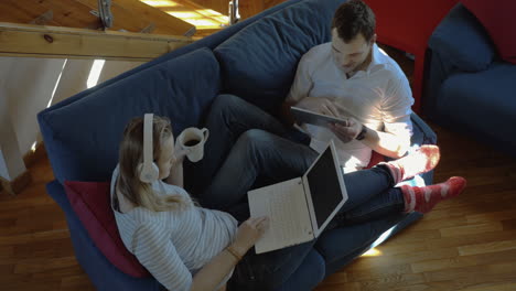 Man-and-woman-at-home-using-pad-and-laptop