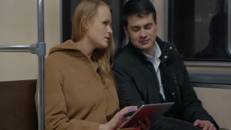 Young-people-using-tablet-computer-in-moving-subway-train