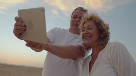 Senior-couple-using-touch-pad-outdoor-on-vacation