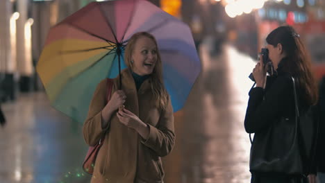 Happy-friends-making-photos-using-retro-camera-in-rainy-city
