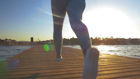 Woman-running-on-wooden-pier-at-sunset
