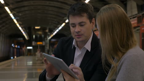 Man-and-woman-passing-time-with-touch-pad-in-the-underground