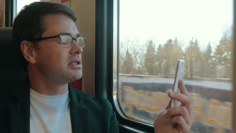 Young-man-video-chatting-on-cell-in-train