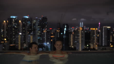 Nachtansicht-Eines-Jungen-Schönen-Paares-Im-Schwimmbad-Auf-Dem-Dach-Im-Vordergrund-Und-Stadtlandschaft-Kuala-Lumpur-Malaysia
