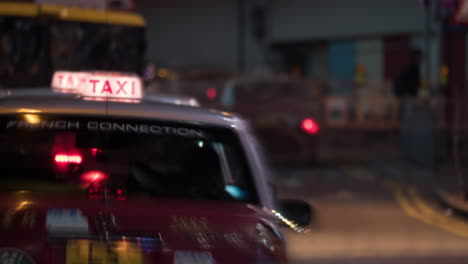 Nahaufnahme-Der-Nachtansicht-Von-Taxis-In-Der-Warteschlange-Wartender-Passagiere,-Verschwommene-Menschen-Im-Verkehr-Im-Hintergrund-Hongkong,-China