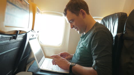 Junger-Mann-Chattet-Im-Flugzeug-Am-Laptop