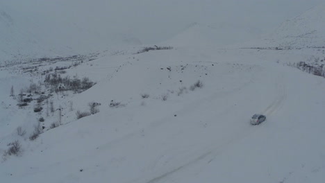 Coche-En-Carretera-Nevada-En-Las-Montañas-Vista-Aérea