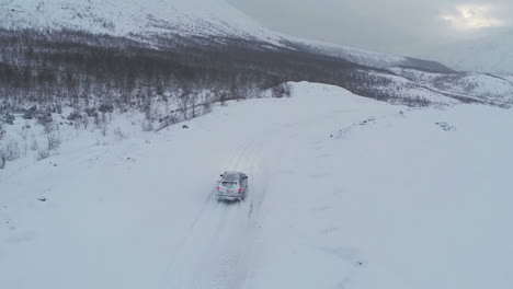 Luftaufnahme-Eines-Autos,-Das-Auf-Einer-Verschneiten-Bergstraße-Fährt