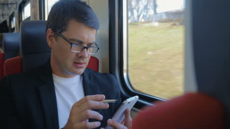 Young-man-using-cell-to-browse-online-in-train