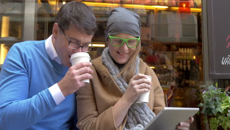 Glückliches-Paar-Mit-Digitalem-Tablet-Im-Straßencafé