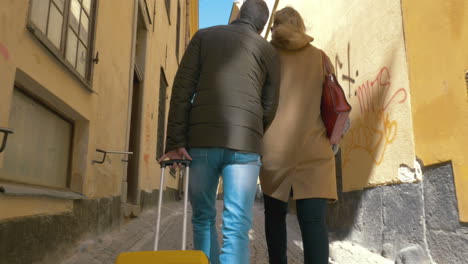 Couple-of-tourists-with-roll-on-bag-walking-in-old-street