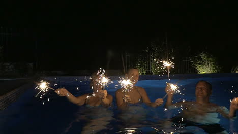 Three-people-having-fun-with-Bengal-fires-in-the-pool