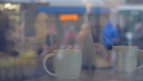 Usando-El-Teléfono-Celular-Y-La-Computadora-Portátil-Durante-La-Pausa-Para-El-Té-En-La-Cafetería