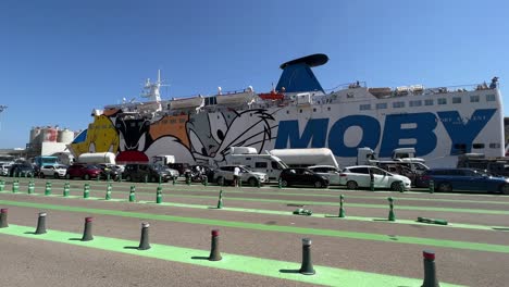 Ferryboat-moored-at-touristic-port-with-passengers-and-cars-queuing-for-boarding