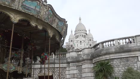 Carrusel-Clásico-De-Montmatre-Girando-En-París-Y-Al-Fondo-Una-Gran-Iglesia,-El-Sacré-Coeur