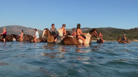 Eine-Gruppe-Von-Touristen-Vergnügt-Sich-In-Der-Sommersaison-Beim-Reiten-Im-Meerwasser