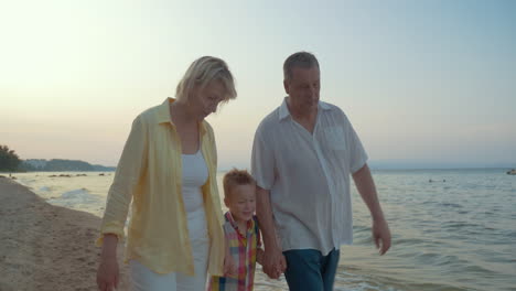 Abuelos-Y-Nieto-Pequeño-Caminando-Por-La-Playa