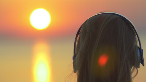 Woman-enjoying-music-and-sunset