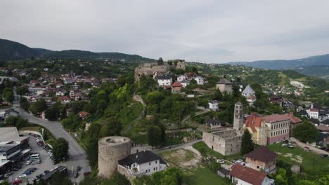Jajce's-Citadel-Amidst-Town-and-Hills,-Aerial-wide-view