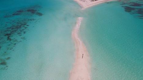 Aerial-approach-couple-stand-on-sandbank-lonely-paradise,-splash-sea-water,-los-Roquues