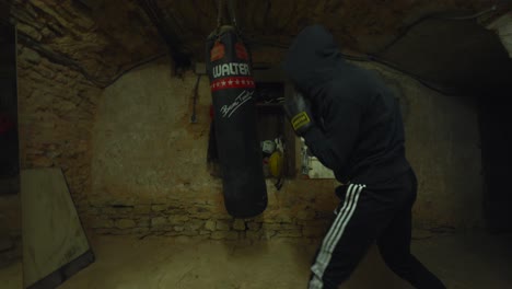 Boxer-clad-in-a-hoodie-unleashes-powerful-punches-on-a-suspended-bag