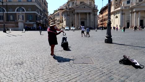 Mujer-Lanza-Dinero-A-Un-Músico-Callejero-En-La-Piazza-Del-Popolo-En-Roma,-Italia