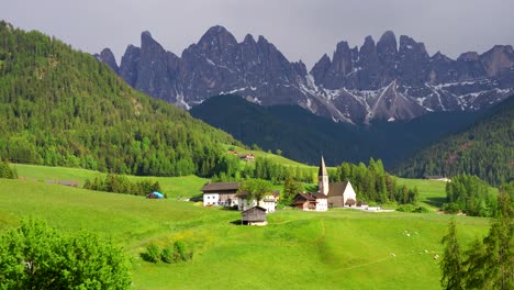 Toma-Panorámica-Izquierda-De-La-Iglesia-De-Santa-Maddalena-Y-La-Cordillera-Odle-Al-Fondo-En-Val-Di-Funes,-Italia