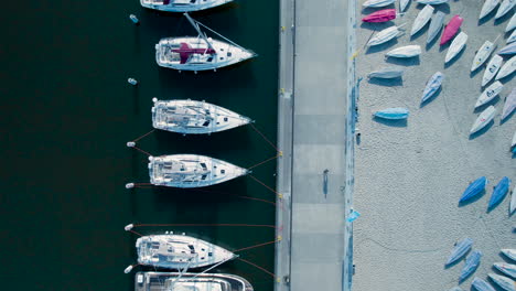 Aerial-top-down-shot-of-Person-walking-on-jetty-on-marina-of-Gdynia-with-anchored-boat