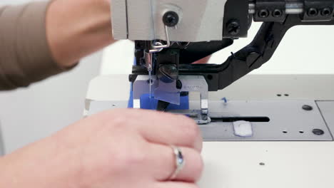 Close-up-of-female-worker-in-a-textile-factory-cutting-holes-for-button-on-piece-of-cloth