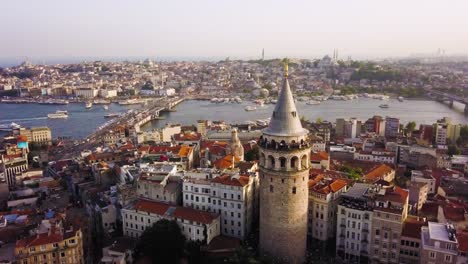 Aerial-circling-Galata-Tower,-boat-traffic-on-Golden-Horn-in-background,-Istanbul
