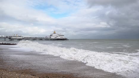 Große-Wellen,-Die-Von-Starken-Winden-Aufgepeitscht-Werden,-Brechen-Am-Strand-Vor-Einem-Vergnügungspier,-Während-Dunkle-Wolken-Aufziehen,-Bevor-Der-Sturm-Ciarán-Auf-Land-Trifft