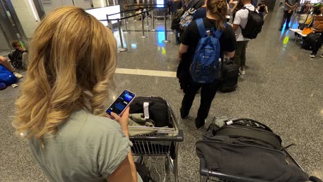 A-girl-at-the-airport-on-the-phone,-waiting-in-line-to-check-in-luggage