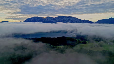 Vista-Aérea-De-Un-Paisaje-Montañoso-Con-Nubes-Bajas-En-El-Lago-Attersee