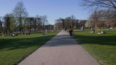 Tranquil-city-park-in-Copenhagen,-with-people-lounging-and-walking-on-a-sunny-day