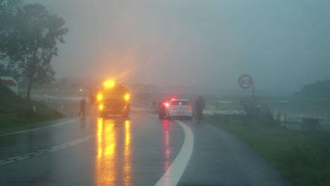 Respuesta-De-Emergencia-A-La-Marejada-Ciclónica-En-Kollund,-Con-Vehículos-Y-Personal-En-Una-Carretera-Lluviosa