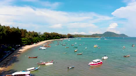 Toma-Aérea-Con-Pedestal-De-Un-Dron-De-La-Extensión-Y-Longitud-De-La-Playa-De-Rawai,-Que-Muestra-Una-Serie-De-Lanchas-Rápidas,-Kayaks,-Botes-De-Madera-De-Cola-Larga-Y-Una-Vista-Panorámica-Del-Mar-De-Andamán,-En-Phuket,-Tailandia