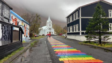 Gente-Caminando-Cerca-De-La-Iglesia-Azul-De-Seydisfjordur,-Pintoresco-Pueblo-En-El-Este-De-Islandia