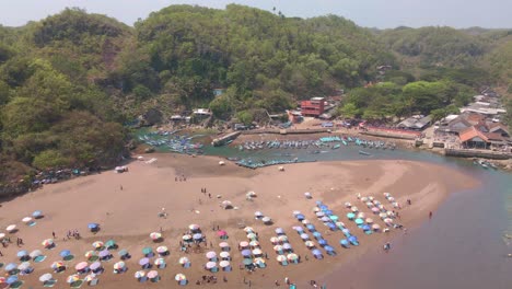 Aerial-view-of-baron-beach-with-colorful-umbrellas-on-the-sandy-shoreline