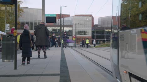 Commuter-train-leaves-passengers-on-platform-on-autumn-Helsinki-street