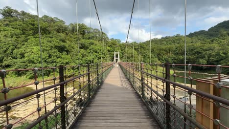 Dolly-in-view-of-a-couple-walking-on-the-Siguangtandiao-Bridge-over-the-Keelung-River-in-Pingxi-District,-New-Taipei-City,-Taiwan