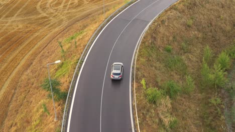 Tracking-a-silver-car-on-the-asphalt-road---aerial-done-shot