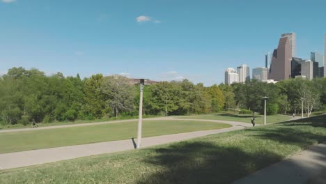 A-young-male-skateboarder-skateboards-through-Eleanor-Tinsley-Park-on-a-sunny-day-with-white-clouds-in-Houston-Texas