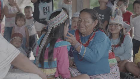 Eine-ältere-Indigene-Frau-Hält-Das-Gesicht-Eines-Jungen-Mädchens,-Das-Von-Ihrer-Gemeinde-In-Peru-Umgeben-Ist
