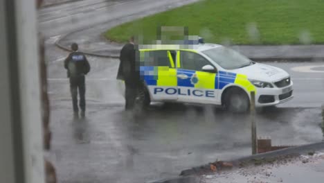 Arrested-male-sitting-in-police-vehicle-with-privacy-mosaic-to-protect-identity,-watching-from-rainy-window