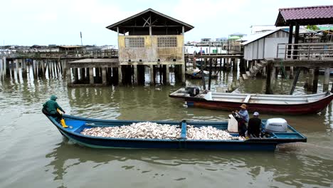 A-capture-of-three-men-onboard-a-fishing-boat-full-of-small-silver-colored-fish-departing-from-the-bay