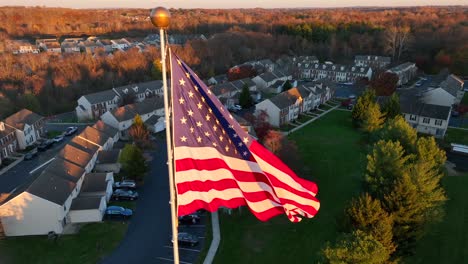 Amerikanische-Flagge-Bei-Sonnenuntergang-Mit-Vorstadthäusern-Im-Hintergrund