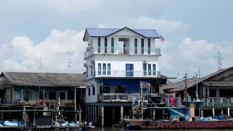 An-image-featuring-the-Malaysian-flag-is-positioned-beside-the-three-story-white-building,-with-the-low-cost-housing-community-situated-below