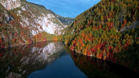 Ein-See-In-Den-österreichischen-Alpen-Mit-Herbstfarben,-Die-Sich-Im-Stillen-Wasser-Spiegeln-–-Luftaufnahme