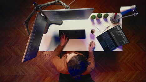 Top-down-view-of-remote-worker-typing-code-in-personal-office