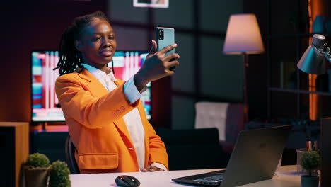 Young-woman-waving-at-phone-videocall-with-tutor-and-classmates